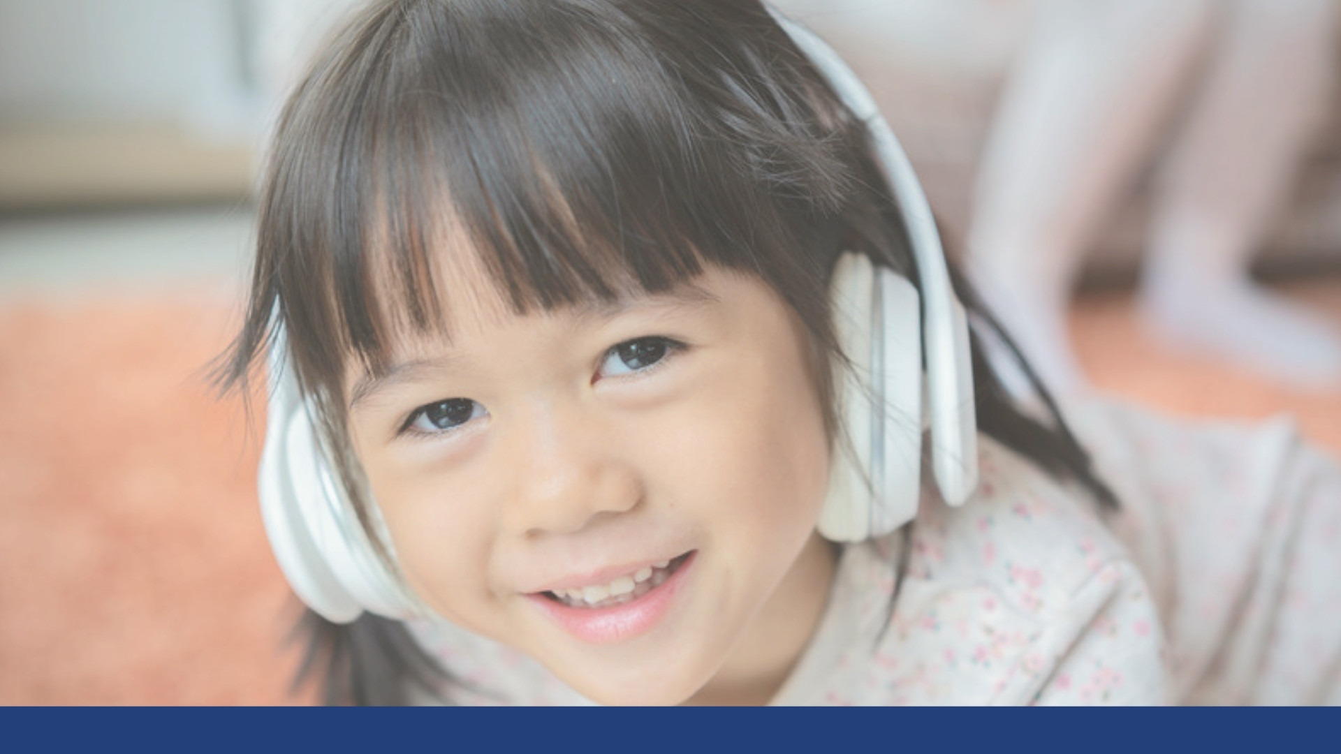 A smiling young girl wearing headphones and listening
