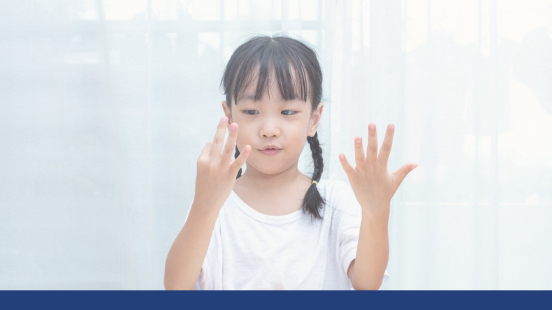 A young girl counting on her fingers at a table at home
