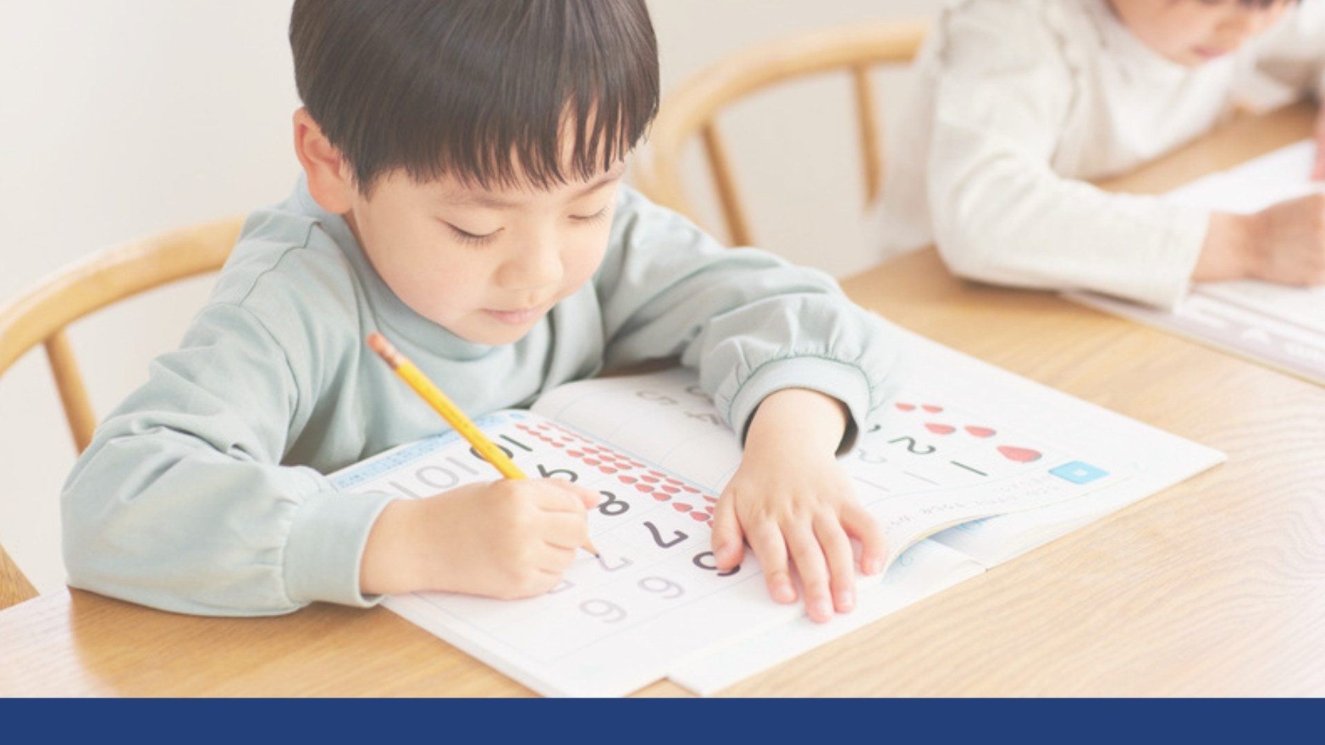 A young boy practicing writing in a workbook at home