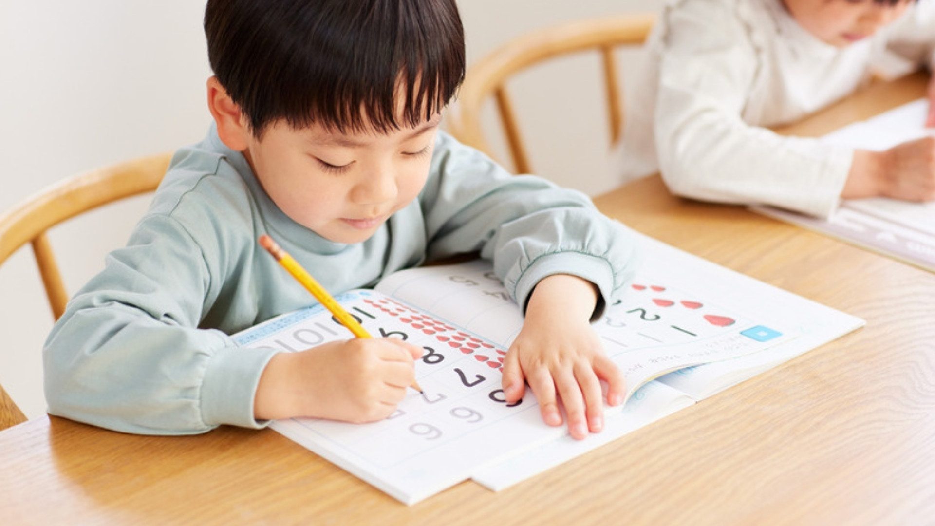 A young boy practicing writing in a workbook at home